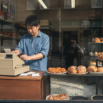 UK shop owner in bakery counting receipts
