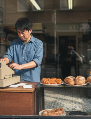 UK shop owner in bakery counting receipts