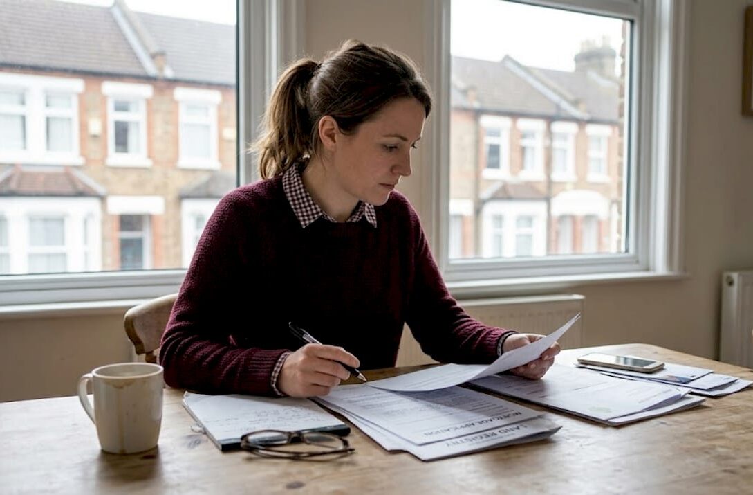 Woman reviewing UK homebuying paperwork at kitchen table