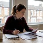 Woman reviewing UK homebuying paperwork at kitchen table